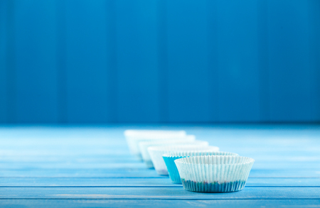 Paper cupcake holder on a blue wooden rustic background.の写真素材