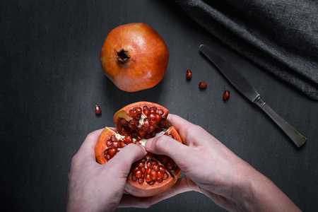 Sliced pomegranate with juicy red grains and knife.の写真素材