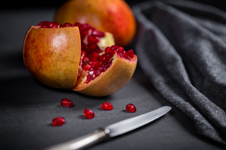 Sliced pomegranate with juicy red grains and knife.の写真素材