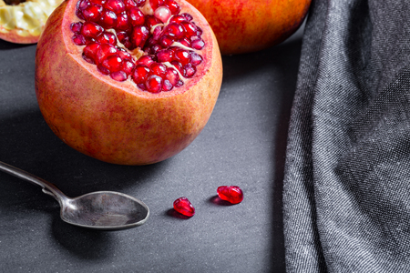 Sliced pomegranate with juicy red grains and spoon.の写真素材