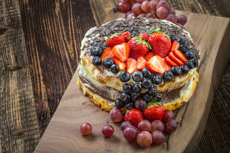 Outstanding fruit cake with strawberries, blueberries, grapes and chocolate. Celebratory tart.の写真素材