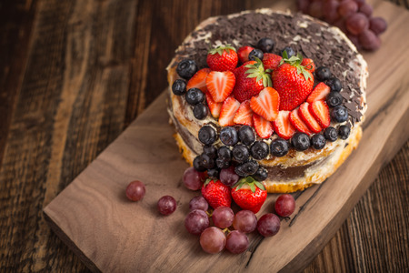 Outstanding fruit cake with strawberries, blueberries, grapes and chocolate. Celebratory tart.の写真素材
