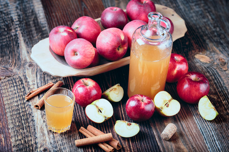 Fresh organic apple cider or apple juice with with cinnamon on the old a wooden table.の写真素材