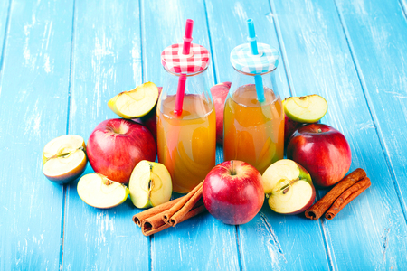 Two bottle fresh organic apple cider or apple juice with with cinnamon on the blue background.の写真素材