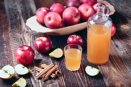 Fresh organic apple cider or apple juice with cinnamon on the old a wooden table.の写真素材