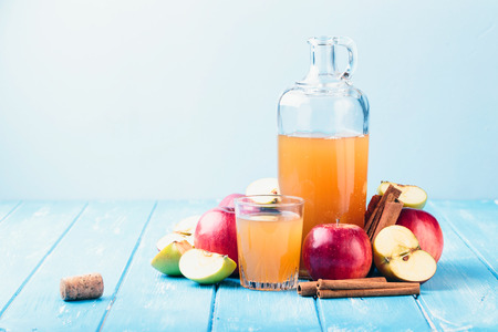 Fresh organic apple cider or apple juice with with cinnamon on the blue background.の写真素材
