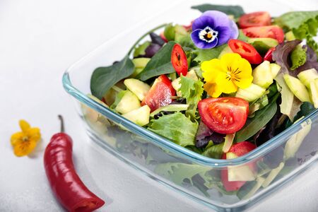 Bowl of vegetable salad with edible flowers and chilli.の写真素材