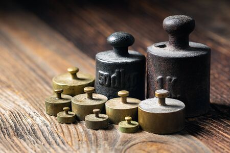 Old rustic metal weights on wooden table.の写真素材