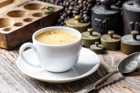 Coffee cup with foam and old rustic metal weightの写真素材