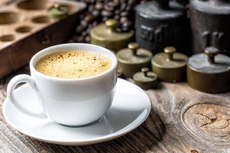 Coffee cup with foam and old rustic metal weightの写真素材