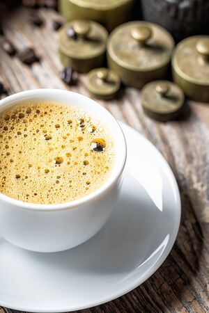 Coffee cup with foam and old rustic metal weightの写真素材