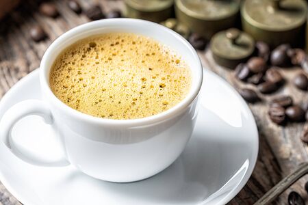 Coffee cup with foam and old rustic metal weightの写真素材