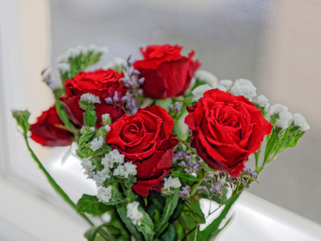 Bouquet of red roses with white carnations on windowの写真素材