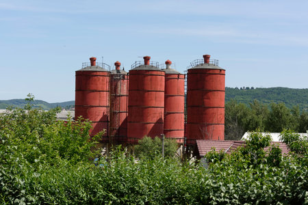 Industrial landscape silos red painted in green natural leavesの写真素材