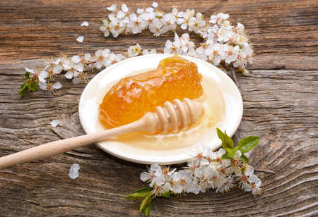 Honey, honeycomb and apricot flowers on wooden backgroundの写真素材