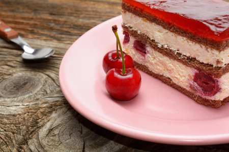 Cherry cake and cherry on wooden background