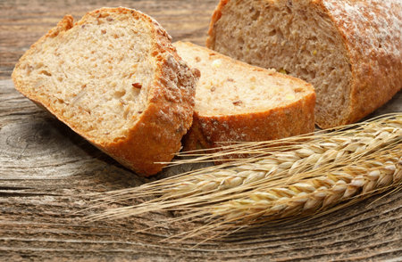 fresh bread and wheat on wooden background