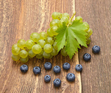 Grapes with leaves on wooden tableの写真素材