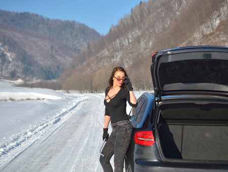 Beautiful young woman posing near a car in winter