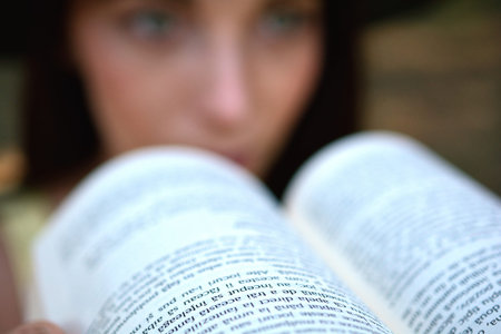 Beautiful Young Woman Reading a Book Outside on the Grass