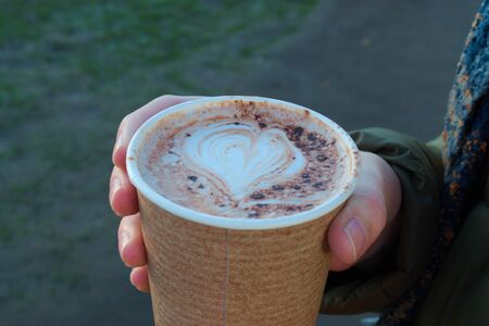 Cardboard coffee cup with a drawing of a heart in the foamの写真素材