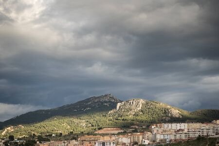 Mountains with sunbeam on a cloudy day and city belowの写真素材