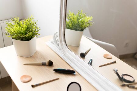 Makeup tools on a wooden table reflected in a mirror with natural lightの写真素材