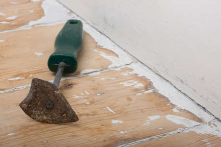Paint scraper resting on partially stripped wood surfaceの写真素材