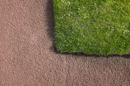 Corner of green grass lawn bounded by red tarmacadam path. Construction  horticultural detailの写真素材