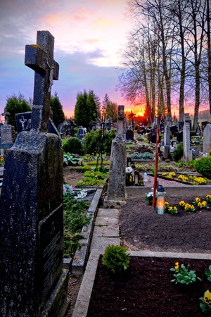 tombstones and silhouettes of crosses and trees against sky at sunset in an old Christian cemeteryの写真素材