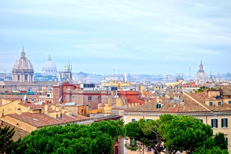 Aerial view of Rome, Italy rooftops in a cityscape looking towards the Petersdom in the distance under a cloudy blue skyのeditorial素材