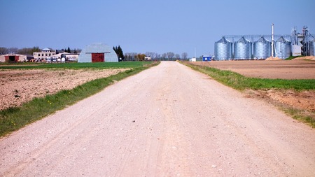 gravel path with silos and hut cabin at the background in Lithuaniaの写真素材