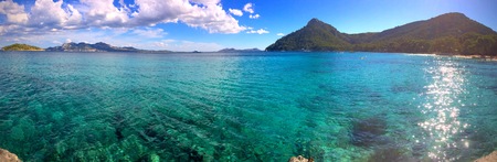 Panorama of a crystal clear blue tropical ocean and distant mountains conceptual of summer vacationsの写真素材