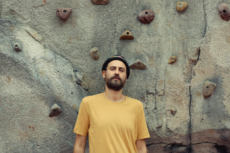 Portrait of a bearded man in a yellow T-shirt on a rock climbing wall