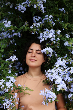 Portrait of a beautiful young woman with blue flowers background