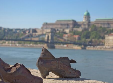 Budapest, April 2019: The shoes memorial on the river bank of the danube with the chain bridge and royal palace in the background.のeditorial素材