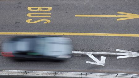 Blurred black car in motion driving next to bus lane.の写真素材