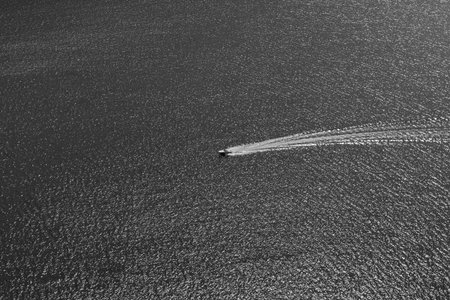 Boat on lake cruising over rippled water minimalist black and white view.