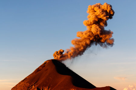 Close up of volcano erupting with orange smoke column at sunrise, clear day near Antigua, Guatemala,...