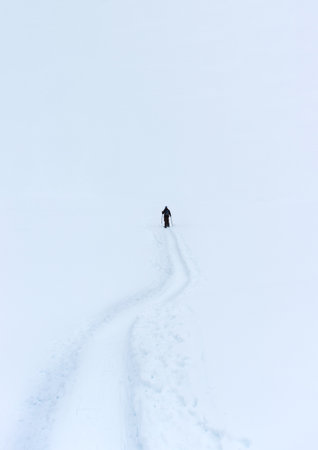 Snow shoe hiking into white nothingness showing concept of lonleiness and solitudeの写真素材