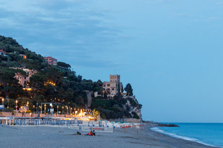 Ligurian Finale beach with houses illuminated at nightの写真素材