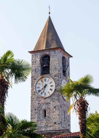 Medieval Clock Tower of Baveno santi gervasio, Italy, through palm trees on sunny day.の写真素材