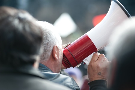 Man with megaphone and tattoo in form of hear on his right hand protesting against communists who gather National Square to protest against the current administration and president elections.のeditorial素材
