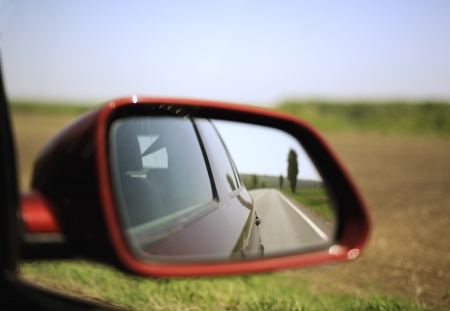 Road and trees reflected in rear-view mirror while driving through agricultural field. Concept file to illustrate an escape to nature from big towns and crowds.の写真素材