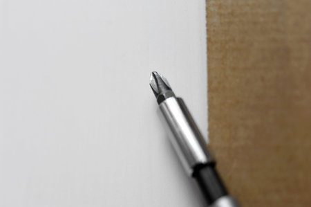 Furniture mounting concept - screwdriver on a white board unpacked a few seconds ago. の写真素材