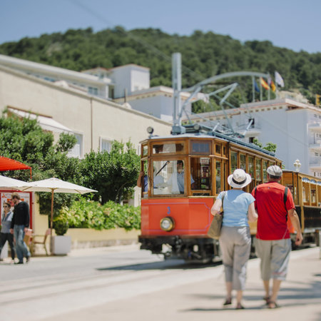 Tourists looking at Orange Express - the historic tram in Port de Soller, Mallorca, Balearic...