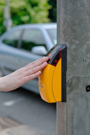 Woman pressing the yellow crosswalk button on the pedestrian crossing の写真素材