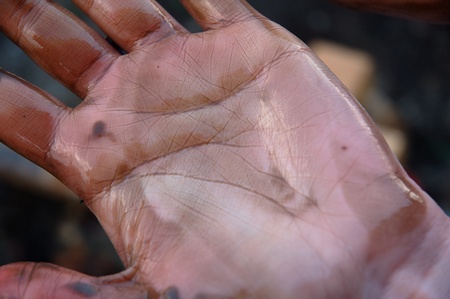 Woman's hand dirty of oil after cleaning the beach of an oil spillの写真素材