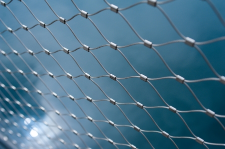 Metallic chain fence link net with blue defocused background. Tilt-shift lense used used to accent the freedom concept and emphasize the attention on them.の写真素材