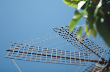 Spanish windmill wing - low angle view from bellow agains blue clear sky and green treeの写真素材